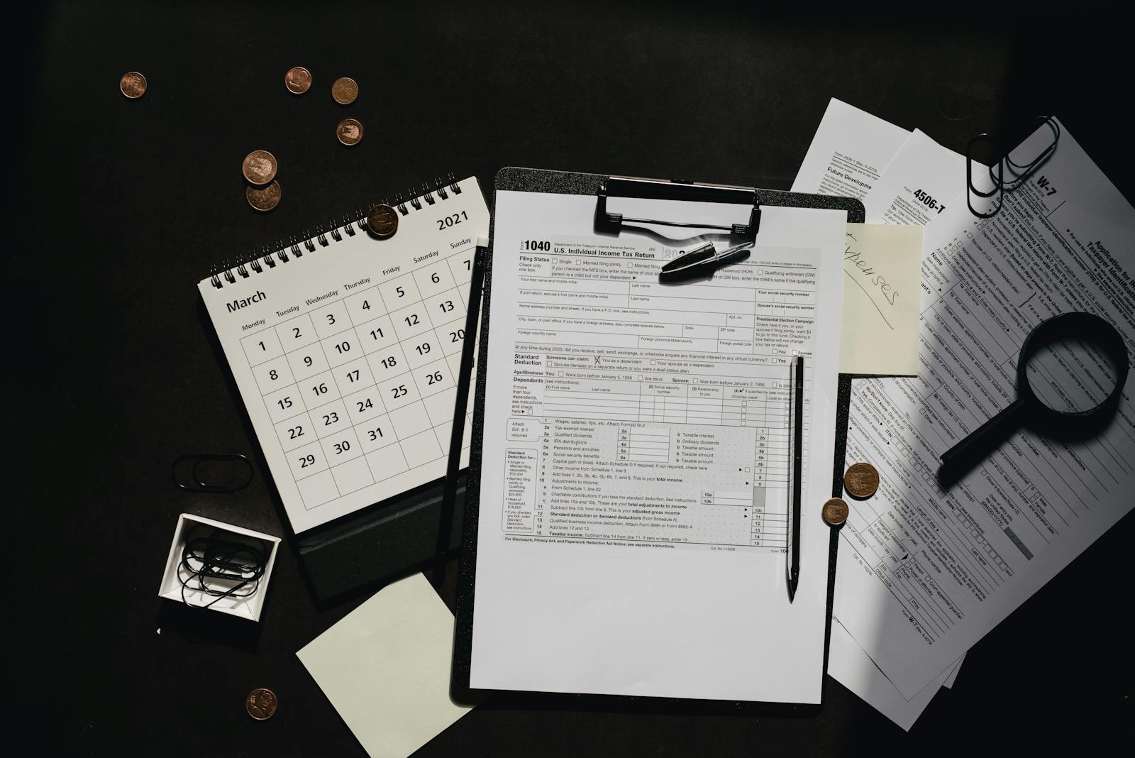 A neatly organized workspace featuring tax forms, calendar, magnifying glass, and office supplies for efficient tax preparation.